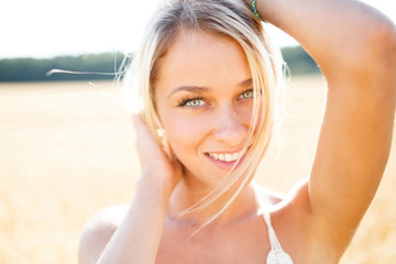 Attractive blonde walking and posing on a rye field in summer da