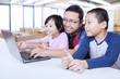 © Creativa Images - Two students using laptop in class with teacher