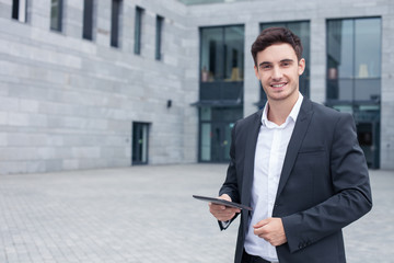 Cheerful young businessman is using modern technology