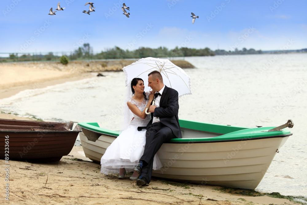 Młoda para w łodzi na jeziorze. - obrazy, fototapety, plakaty 