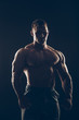© satyrenko - Handsome muscular bodybuilder posing over black background.