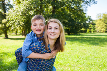 son hugging young mother in the park
