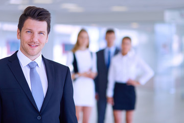 Portrait of young businessman in office with colleagues in the