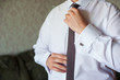 © lisovoy - Man in a white shirt with cuff links, straightens his tie