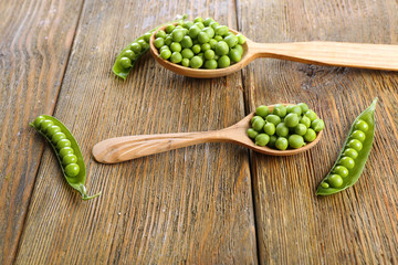 Fresh green peas in wooden spoon on table close up