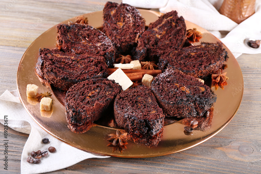 Delicious chocolate roll on metal plate on wooden table, closeup