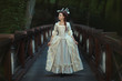 The girl in an old ball dress walking on bridge.