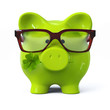 Green piggy bank with glasses and four leaf clover
