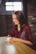 © WavebreakMediaMicro - Smiling brunette enjoying cup of coffee