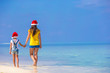 © travnikovstudio - Little girl and young mother in Santa Hat during beach vacation