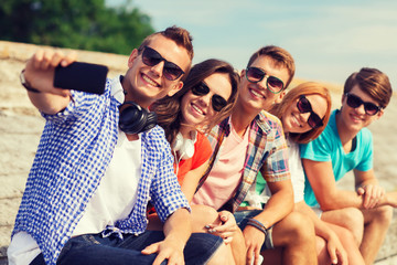 Wall Mural - group of smiling friends with smartphone outdoors