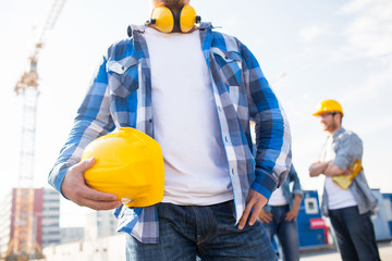 Wall Mural - close up of builder holding hardhat at building