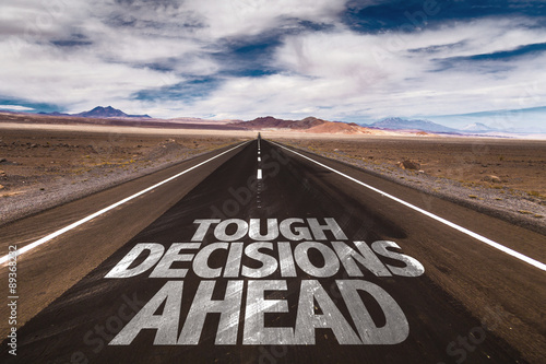 Photo  Tough Decisions Ahead written on desert road