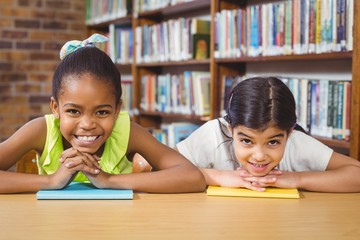 Smiling pupils leaning on books in the library