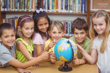 Pupils in library pointing to globe