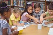 © WavebreakmediaMicro - Pupils working together at desk in library