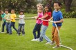 © WavebreakMediaMicro - Cute pupils playing tug of war on the grass outside