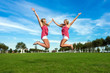 © abasler - two pretty girls jumping in park holding hands