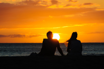 Wall Mural - Couple watching the sunset on a beach in Maui Hawaii USA