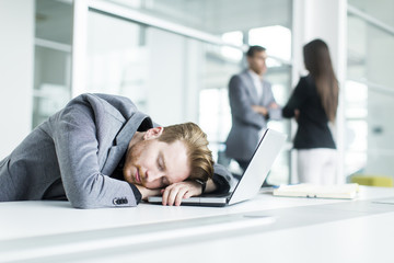 Wall Mural - Tired young man sleeping in the office