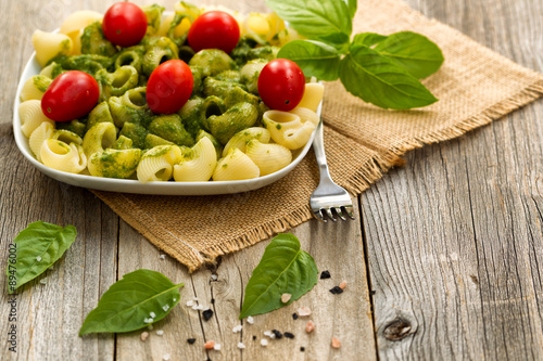 Poster Traditional basil pesto dish with cherry tomatoes on rustic wood