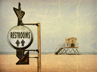 Wall Mural - aged and worn vintage photo of lifeguard tower on beach sand and restroom sign