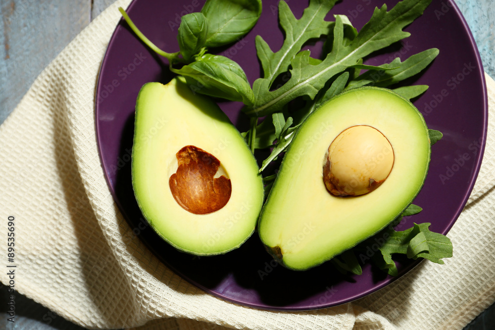 Sliced avocado, arugula on wooden background