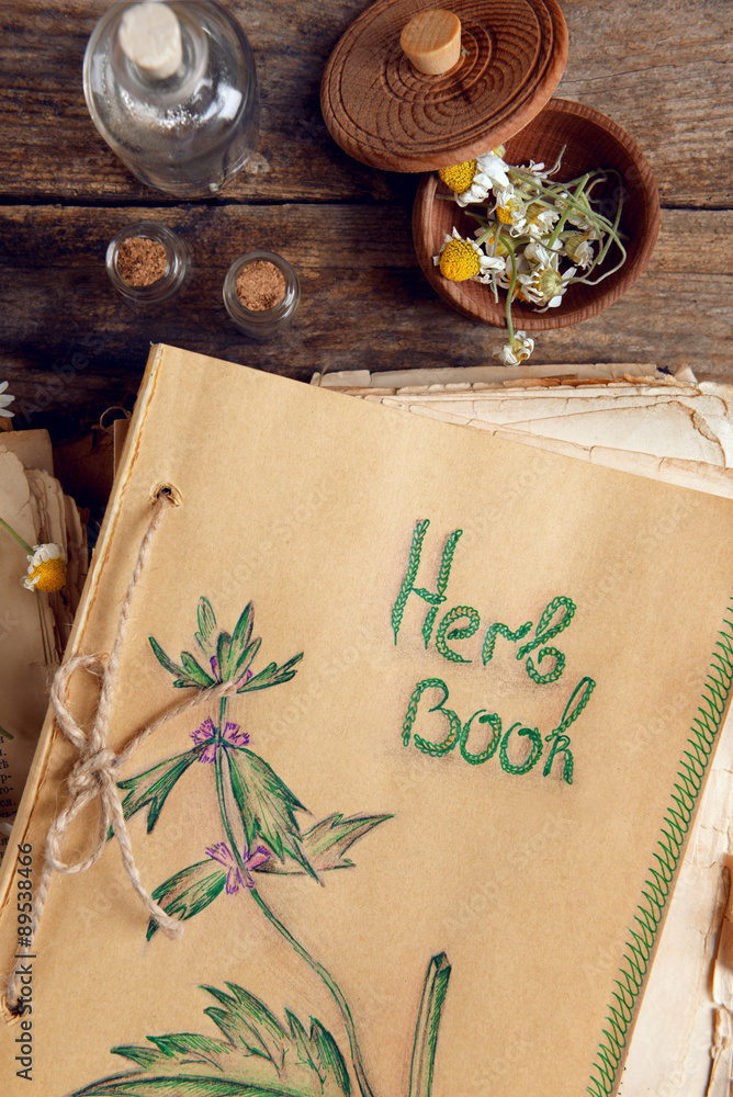 Old book with dry flowers in mortar on table close up