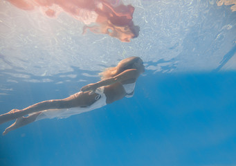 Wall Mural - Young woman swimming underwater