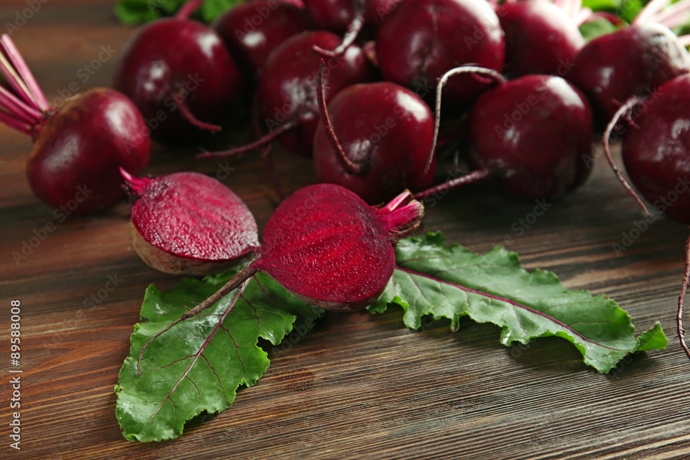 Young beets with leaves on wooden table close up