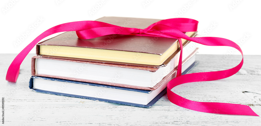 Stack of books with ribbon on table isolated on white