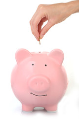 Poster - Female hand putting coin into piggy bank isolated on white