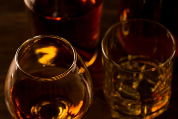 Wall Mural - glass of whiskey with ice and a bottle on a wooden table. Cognac, brandy.