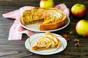 Apple tart, shortcrust pastry pie with walnuts on a wooden backg