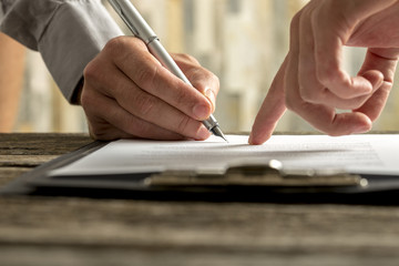 Closeup of employer showing his new employee where to sign an em