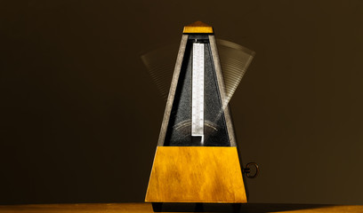 wooden mechanical metronome with motion blur arm
