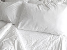 Detail Of Bed With Set Of Crisp White Sheets And Pillows    