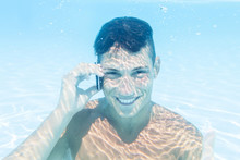 Young Man Takes A Call To Smartphone Underwater
