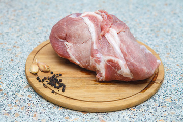 large piece of raw meat with pepper and garlic on a cutting boar