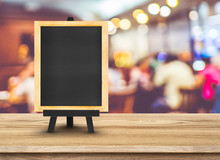 Blackboard Menu With Easel On Wooden Table With Blur Restaurant