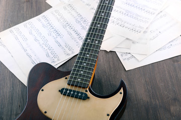 Canvas Print - Electric guitar with music notes on wooden table close up