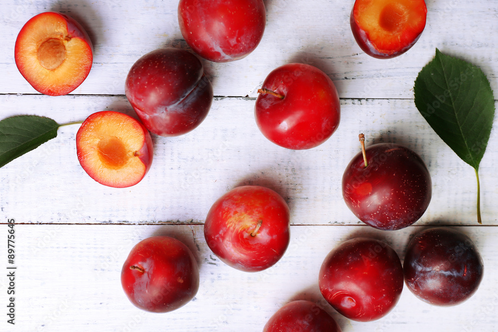 Ripe plums on white wooden background