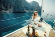 Leinwandbild Motiv Luxury vacation at sea on yacht. Beautiful woman with wine, fruit and mobile phone on boat
