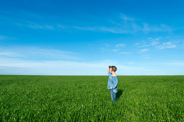 woman standing and looking far away in green field