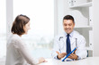 © Syda Productions - smiling doctor and woman with tablet pc at clinic
