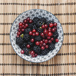 bowl with wild blackberries and redcurrants on a bamboo tableclo