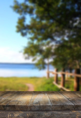 Vintage wooden board table in front of dreamy and abstract forest lake landscape