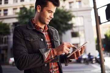 handsome man in down town los angeles using tablet on the go