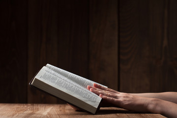 Wall Mural - woman reading the bible in the darkness over wooden table