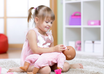 beautiful girl playing doctor with a doll